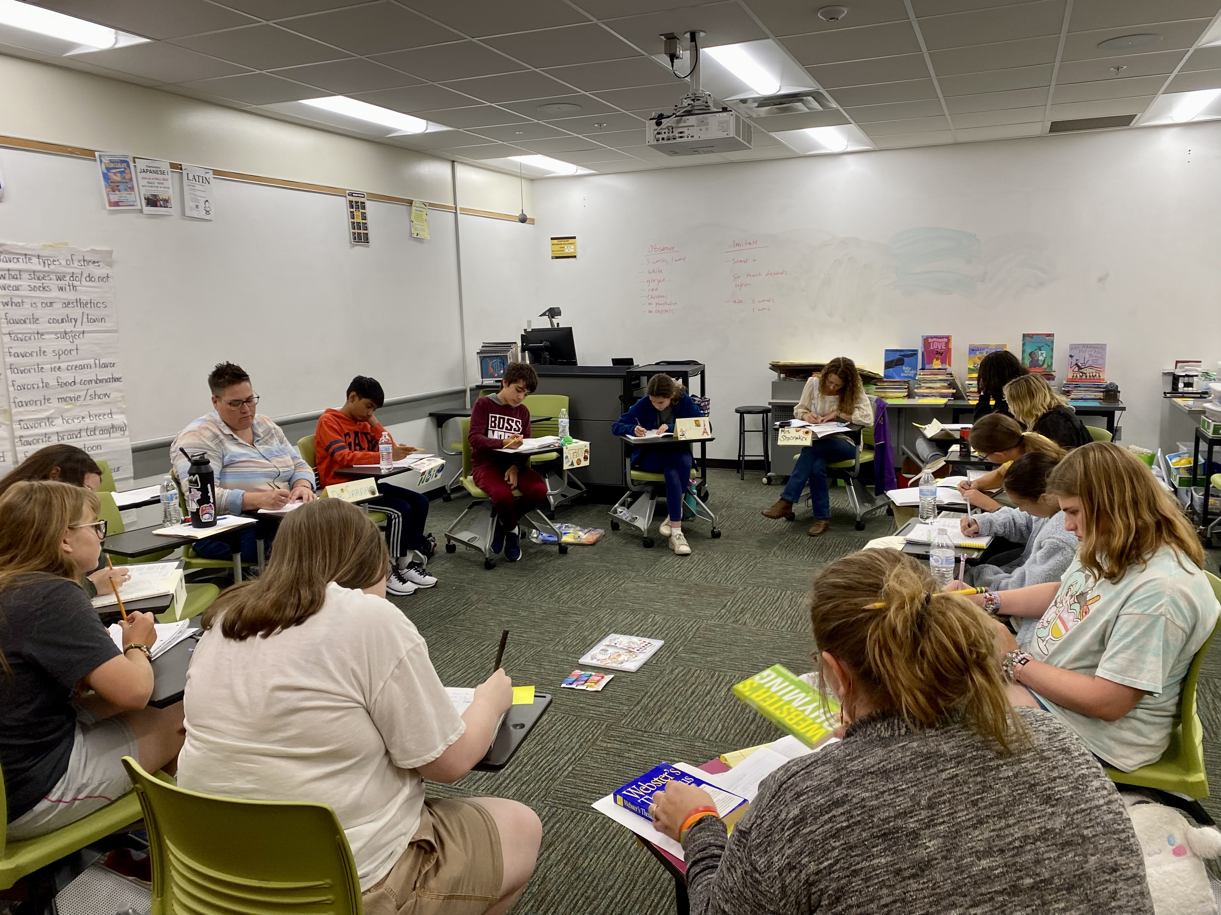 A group of student sit at their desks arranged in a circle.